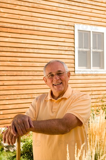 Senior man standing in front of house