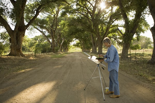 Woman painting in rural scenery