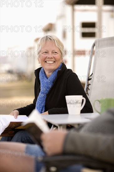 Senior couple reading book outside mobile home