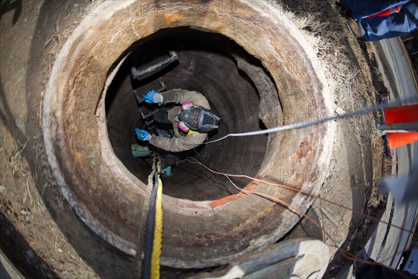 Worker in manhole installing cable