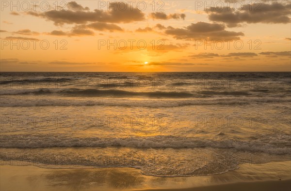 Golden sky with sun and calm ocean at sunset