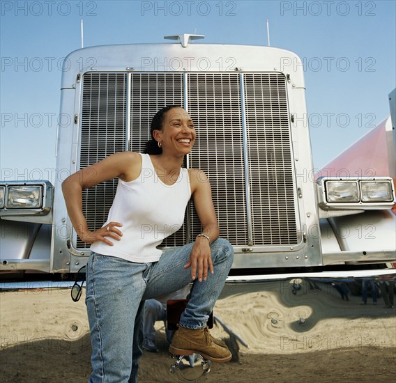 Female truck driver leaning on her vehicle