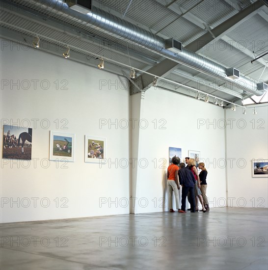 Group of people looking closely at photograph in art gallery