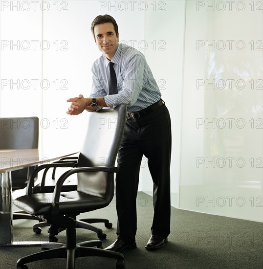 Businessman leaning on chair in boardroom