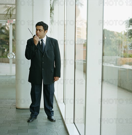 Building security guard holding two way radio in lobby