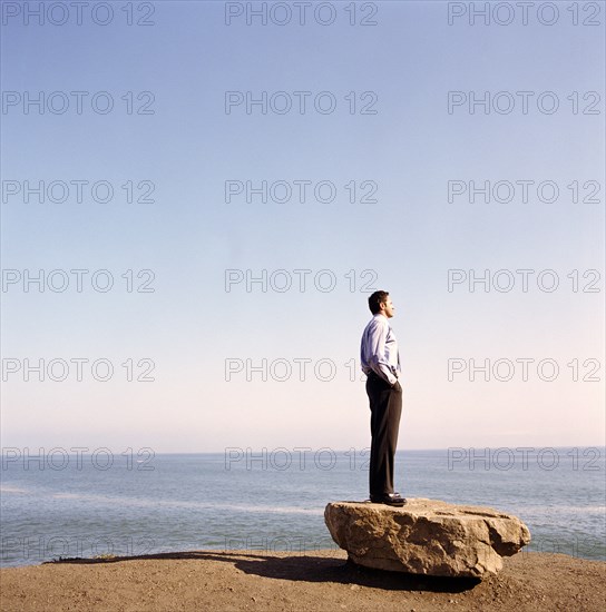 USA, California, Point Mugu, Businessman standing on rock on beach