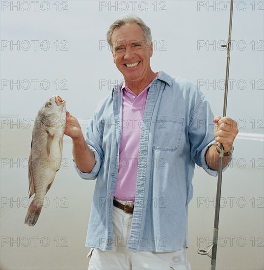 Portrait of smiling fisherman holding catch
