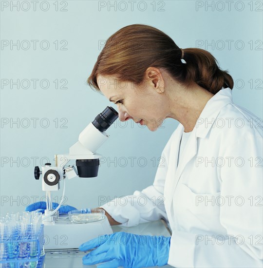 Lab technician looking through microscope