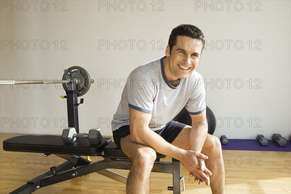 Portrait of man sitting on weight bench