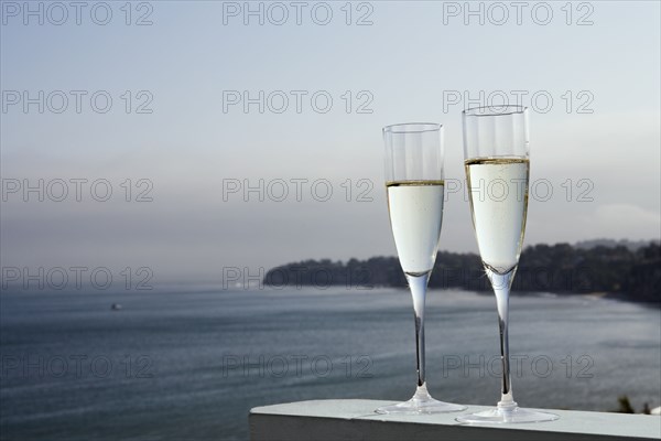 Two glasses of champagne with sea in background