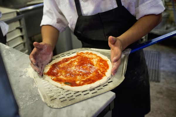 Man placing pizza on pizza peel