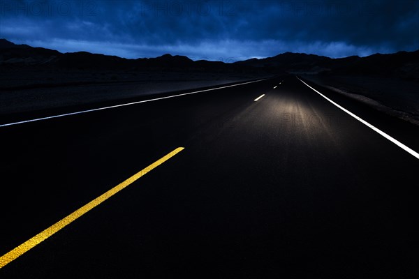 Empty highway at night with car headlights