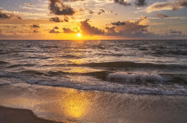 Ocean waves washing beach at sunrise