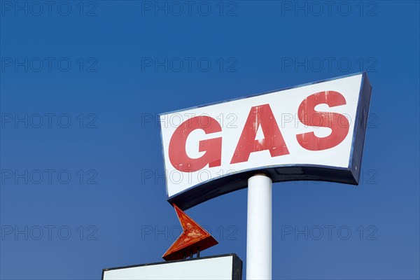Low angle view of vintage gas station sign against sky