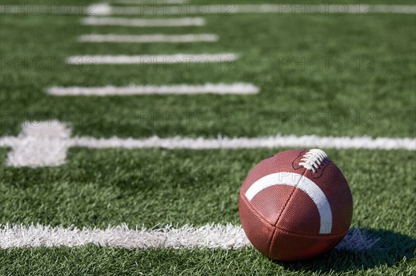 American football ball at yard line markers on playing field