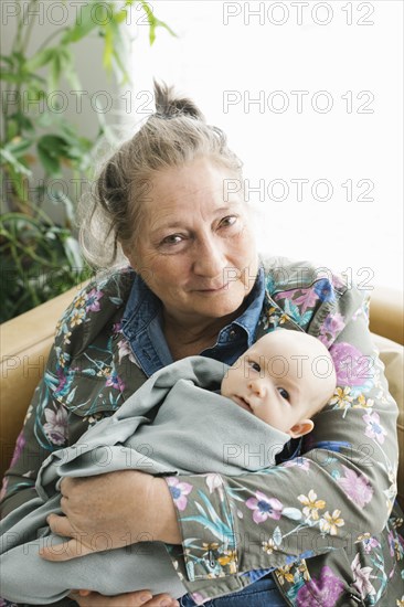 Portrait of smiling grandmother holding newborn grandson