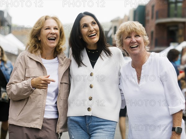 Three women walking through street market