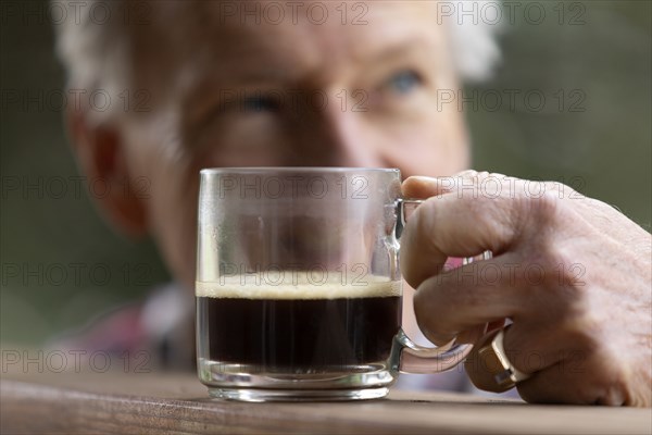 Senior man reaching for coffee cup