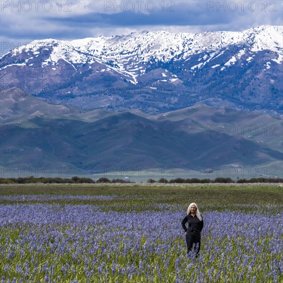 Senior woman standing in field of camas lilies with Soldier Mountain in background