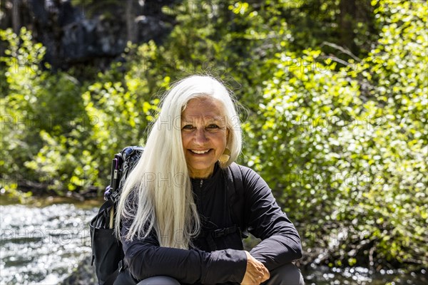 Senior blonde woman resting by rushing stream near Sun Valley