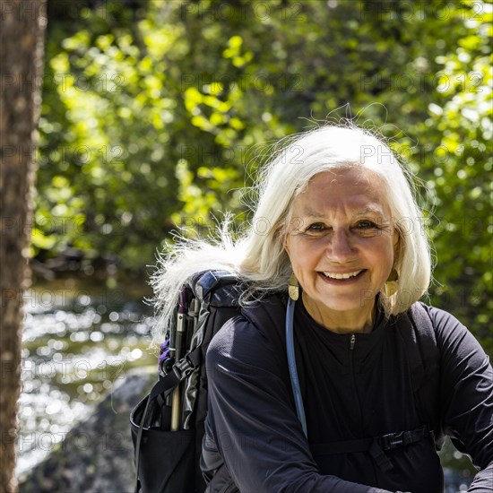 Senior blonde woman resting by rushing stream near Sun Valley