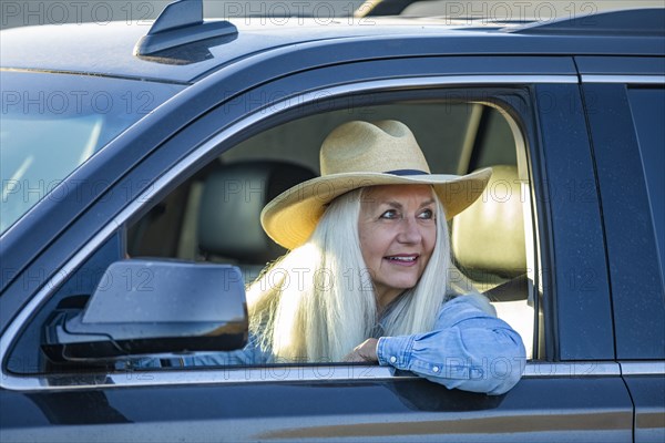 Senior woman in car wearing cowboy hat