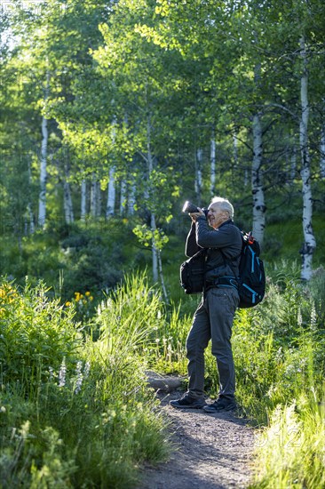 Senior man taking photographs while hiking