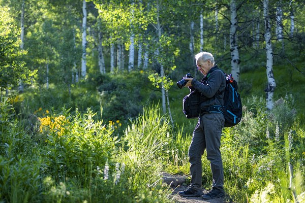 Senior man taking photographs while hiking