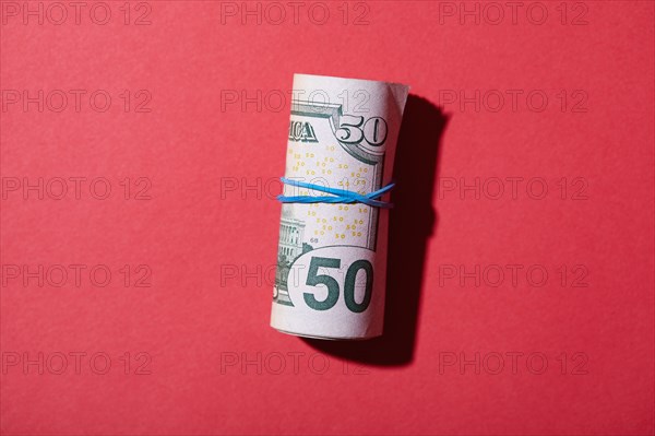 Rolled up fifty dollar bills against red background