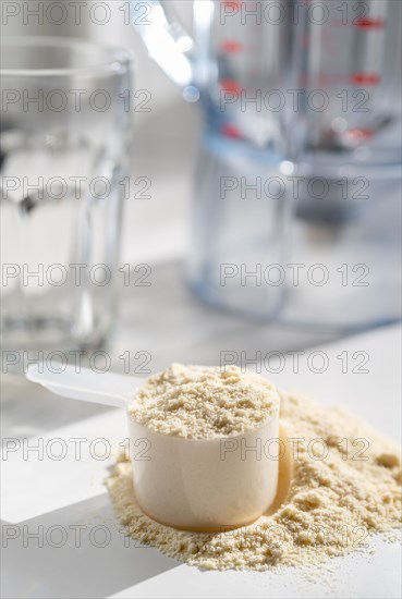 Protein powder in a plastic measuring cup with smoothie glass