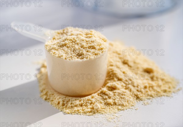 Cup of protein powder on white table