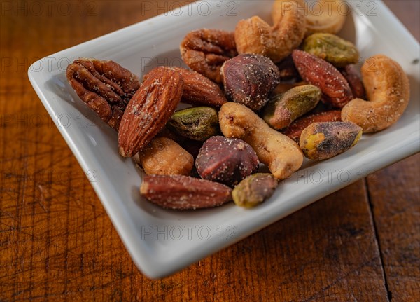 Close-up of small dish of assorted nuts on wooden table