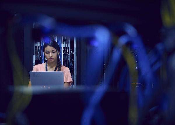 Female technician using laptop in server room