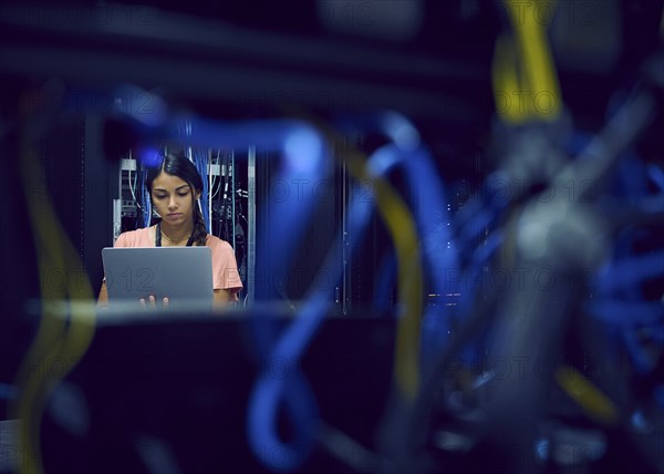 Female technician using laptop in server room