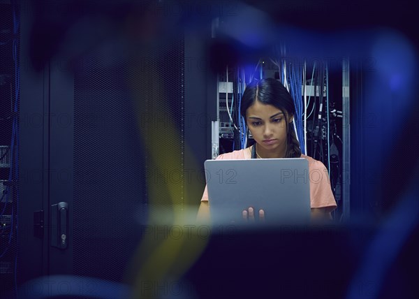 Female technician using laptop in server room