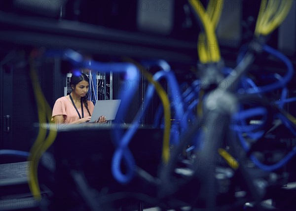 Female technician using laptop in server room