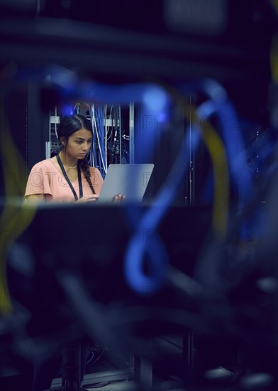 Female technician using laptop in server room