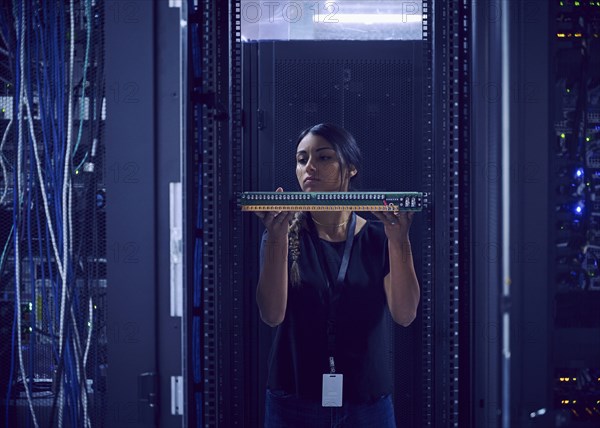 Female technician holding hard drive in server room
