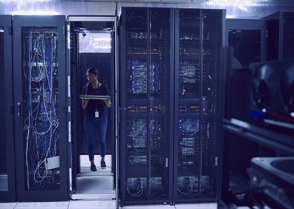 Female technician carrying hard drive in server room