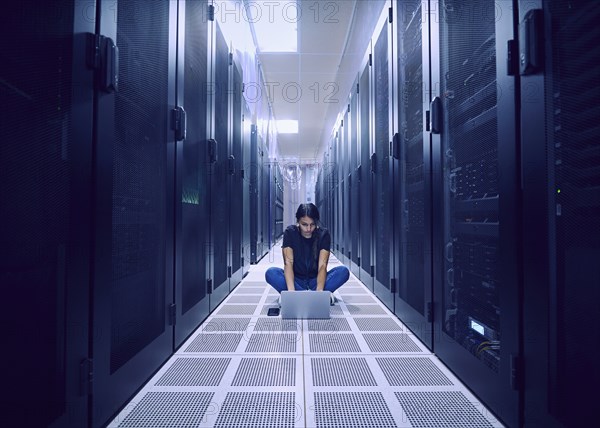 Female technician using laptop on floor in server room
