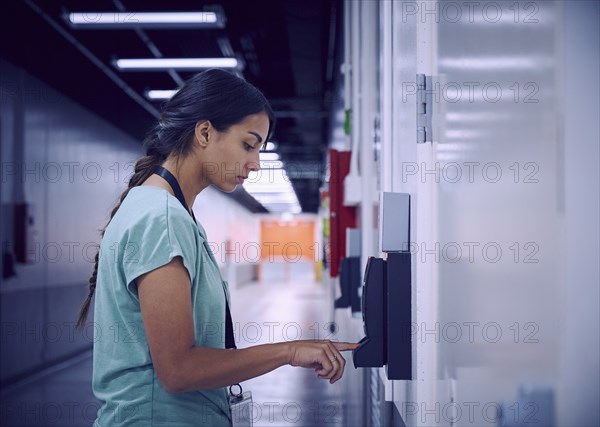 Woman using digital fingerprint scanner in office