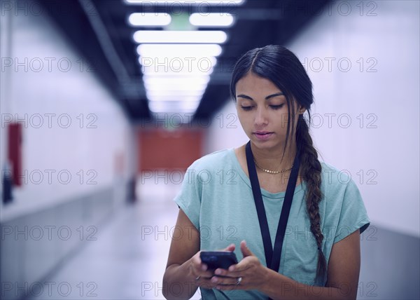 Female technician looking at smart phone in data center