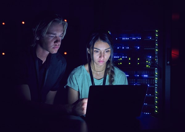 Technicians using laptop in server room