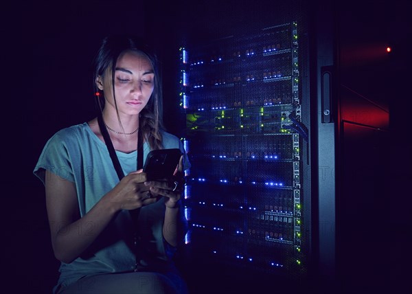 Technician using smart phone in server room