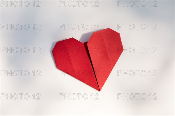 Red origami heart on white background