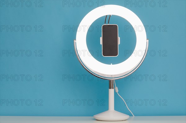 Ring light and smart phone on blue background