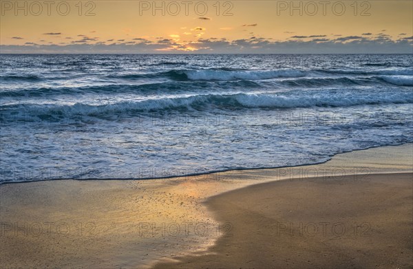 Ocean waves washing beach at sunset