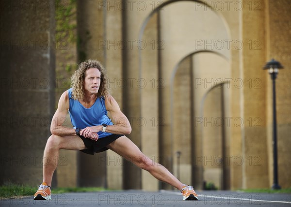 Runner stretching under bridge