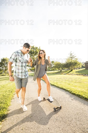 Smiling couple with skateboard in park