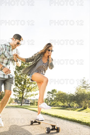 Smiling couple with skateboard in park